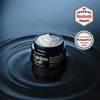 A jar of the hydro layer by Caldera + lab shown on water with the top removed the moisturizer cream visible
