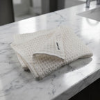 Folded textured face towel  on a marble bathroom counter.